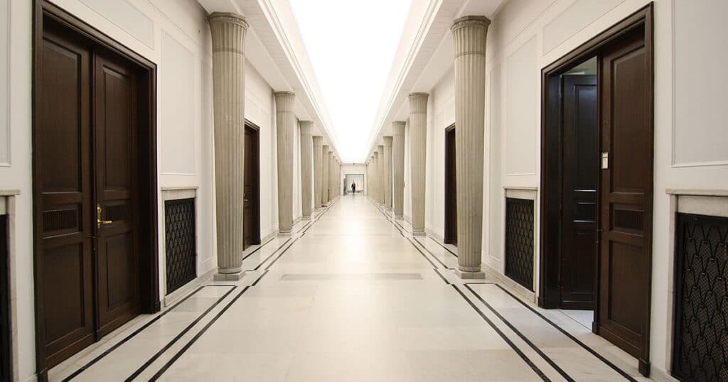 Classroom hall with black doors and white pillars.