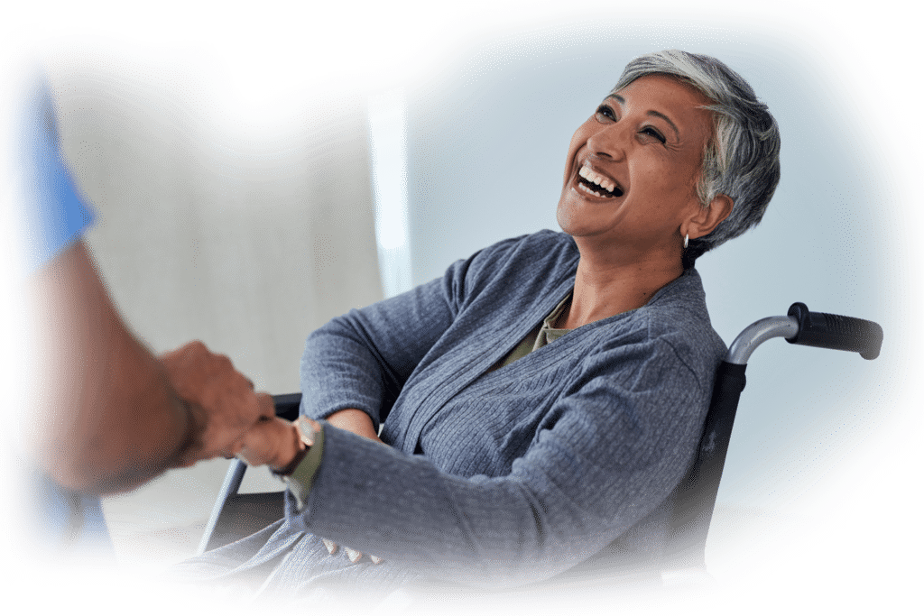 A happy woman with a disability in a wheelchair shaking hands with her caretaker.