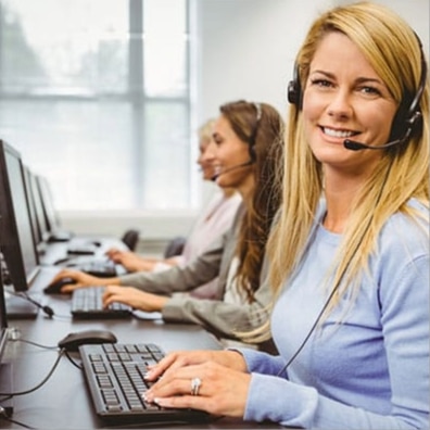 Woman working in a call center with a phone headset on smiling and looking into the camera